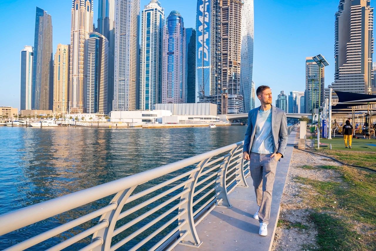 Jeune homme marchant sur la promenade de Dubai Marina. Bel homme d'affaires se tenant debout à Dubai Marina, réfléchissant à des idées commerciales.