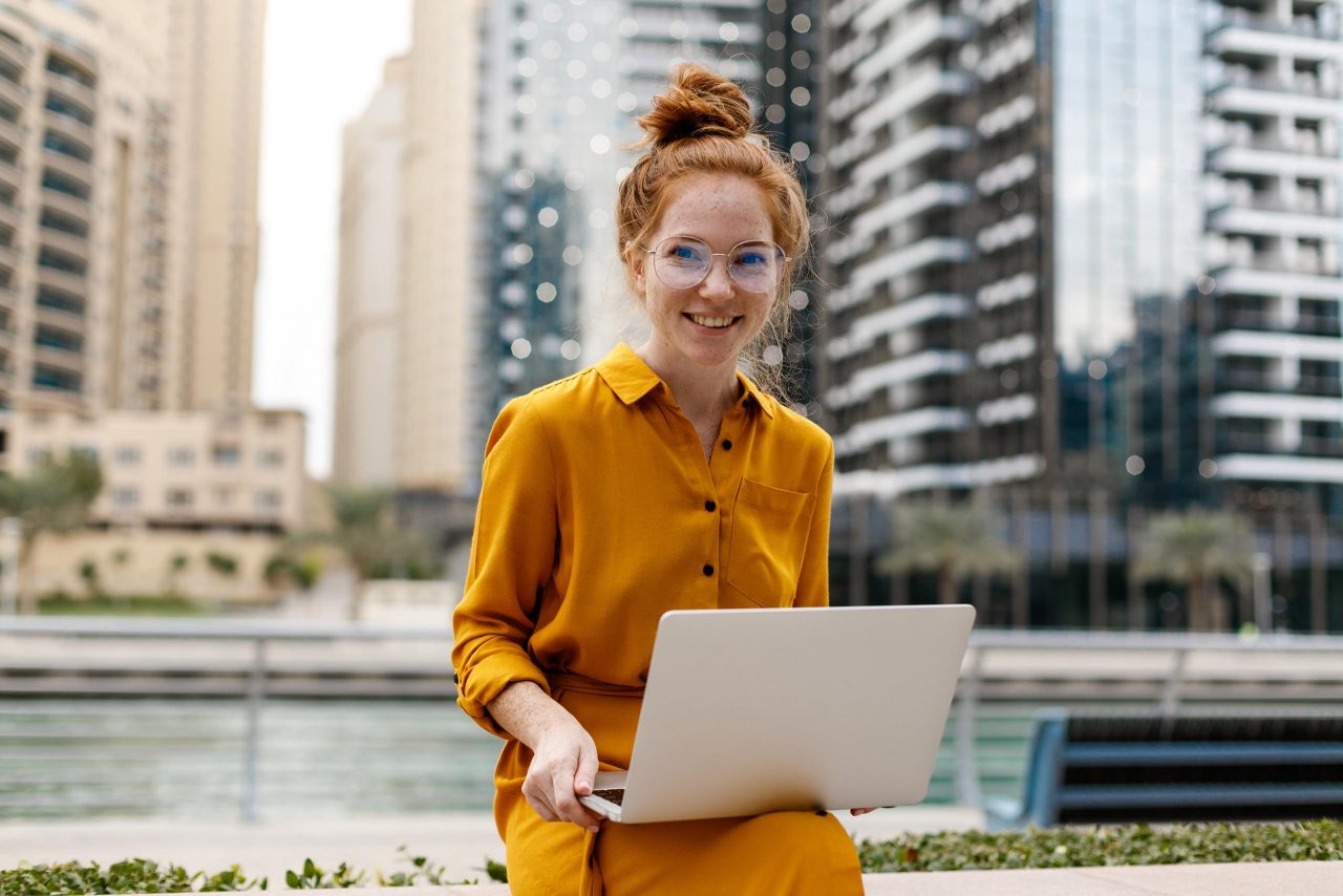 Jeune étudiant assis dans le quartier de Dubai Marina avec un ordinateur portable ouvert