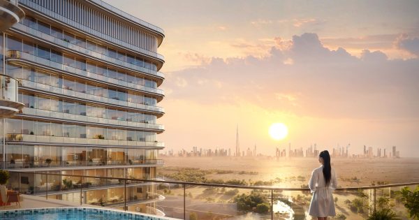 Femme sur un balcon avec la silhouette de Dubaï au coucher du soleil